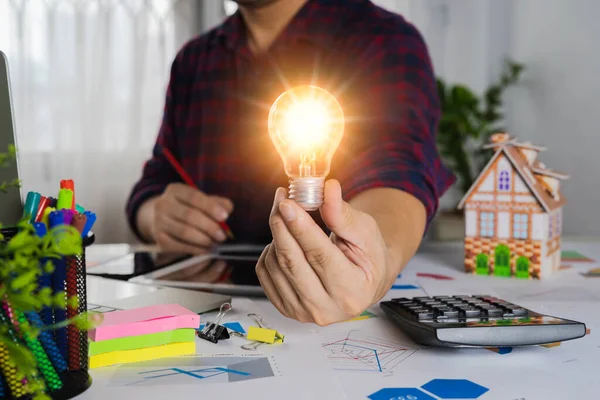 Human Hand Holds Light Bulb Presses Calculator Calculate Company Energy — Stock Photo, Image