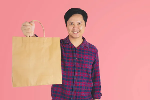快乐的40岁年轻人带着纸袋购物 带着粉红的背景向前看 — 图库照片
