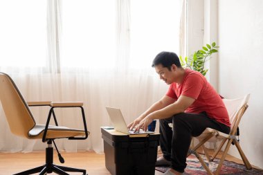 Evde dizüstü bilgisayar kullanan yakışıklı bir adam. Odasında dinlenen adamlar. Çevrimiçi alışveriş, ev işi, serbest çalışma, çevrimiçi öğrenme, öğrenim kavramı. Uzaklık eğitimi