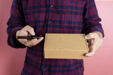 Küçük bir işletme, KOBİ sahipleri, Erkek Girişimciler müşterilere satılacak kutuları hazırlamak için müşterinin adını ve adresini doğrulamak için akıllı telefon kullanarak resim çekiyorlar