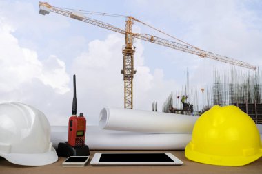 control concept. The construction of a large building, structure building with a crane was installed on, the front desks of the engineers, with helmet, Tablet, radio, schematic drawings placed. clipart