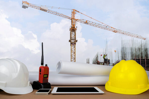 control concept. The construction of a large building, structure building with a crane was installed on, the front desks of the engineers, with helmet, Tablet, radio, schematic drawings placed.