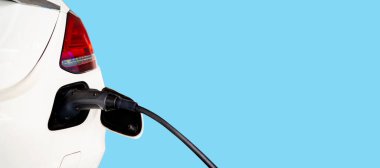 Elektrikli araba şarjı için güç kaynağı. Elektrikli araba şarj istasyonu. Beyaz elektrikli araba mavi arkaplandaki elektrik santraline bağlı.