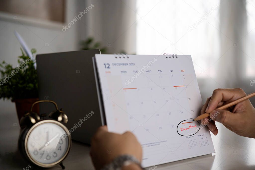 Deadline written on a calendar. Businessmen are circled on December 31st, the last day of the year.