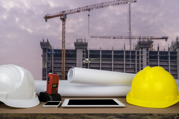 control concept. The construction of a large building, structure building with a crane was installed on, the front desks of the engineers, with helmet, Tablet, radio, schematic drawings placed.