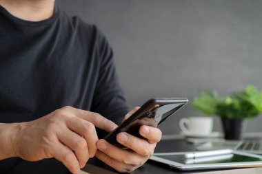 Mutlu Genç Adam evdeki koltukta otururken akıllı telefon kullanıyor. Man İnternet 'e Bakar, Video İzler ve Evde Sosyal Ağ Kullanır.