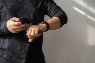 Ofiste akıllı saat ve akıllı telefon kullanan bir adam. Ekranda yeni ileti alındı