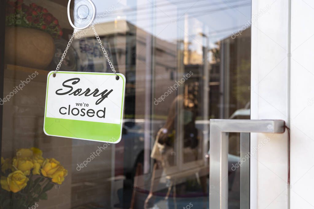 Sorry we're closed sign. grunge image hanging on a dirty glass door.