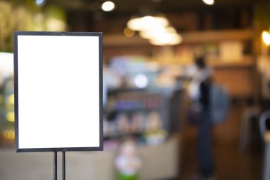 Promosyon ürün konsepti için siyah çerçeveli model beyaz afiş bulanık restoran kafesinin arka planında