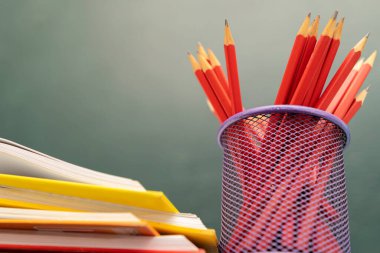 Eğitim arka plan kavramı. Kitap ve ahşap masa üzerinde kalem ile siyah kara tahta arka plan olarak açıldı. Öğretmen masası.