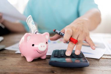 Erkek el kalemi, hesap makinesi, kumbara, para ve büyüteç. Domuzcuk bankasına para yatırmak ve yakın çekim hesaplarına güvenmek.