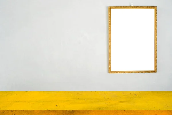 A yellow iron table in front of a cement wall with a golden frame. White label floor for text, images, advertising media.