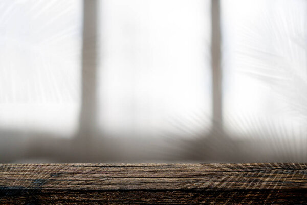 Wood table background with sunlight window create leaf shadow on