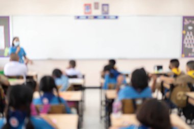 Arka plan kullanımı için sınıfta bulanık çocuklar ve öğretmen var. Öğretmen sınıfın önünde duruyor..