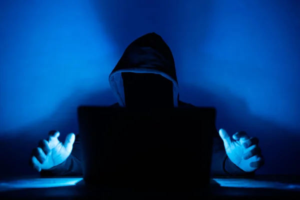 Cybersecurity, computer hacker with hoodie and obscured face. Hacker in front of his computer. Dark face