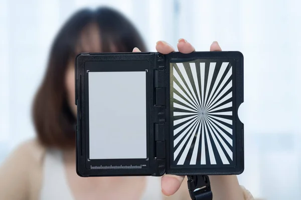 Custom white balance in the hands of a girl. The model holds a custom white balance in its hands for white balance transfer during further.