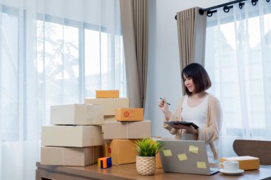 İş yerinde bilgisayarla küçük bir iş kurma. Serbest çalışan kadın satıcı ürün siparişini kontrol ediyor. İnternet üzerinden satıyor.Online alışveriş. KOBİ, E-ticaret.