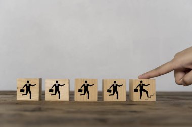 Tahta bir bloğa dokunan parmaklar, bir iş adamını tahta bir blokta kariyerinde ilerlerken resmediyor. İş geliştirme ve büyüme kavramı.