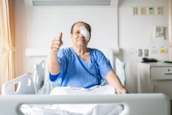 Treatment of post-operative cataract by the concept of caregiver an old asian man put a protective shield over her eyes to cover the cover to protect during nap time.