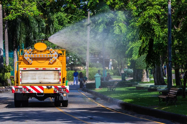 公共の公園で水滴の霧を示す大きなタンク スプレーで水をまく — ストック写真