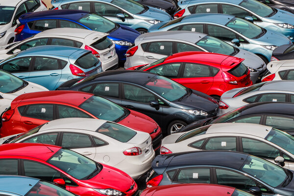 Brand new Motor Vehicles crowed in a Parking lot waiting for Distribution to Dealers