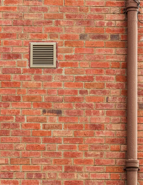 Pared de ladrillo marrón viejo con ventilación y tubería vieja —  Fotos de Stock