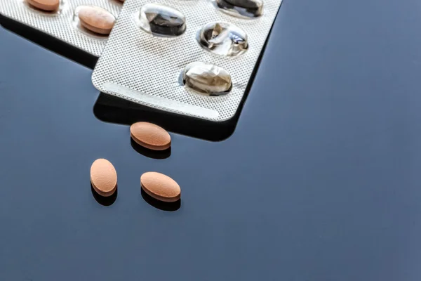 Medicinale ovale tabletten en blister pack op glas achtergrond — Stockfoto