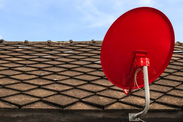Prato receptor de TV por satélite vermelho no telhado telhas velhas — Fotografia de Stock