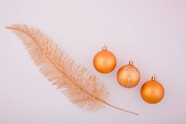 Three yellow shiny Christmas balls and yellow feather — Stock Photo, Image