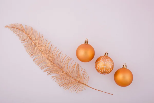 Three yellow shiny Christmas balls and yellow feather — Stock Photo, Image