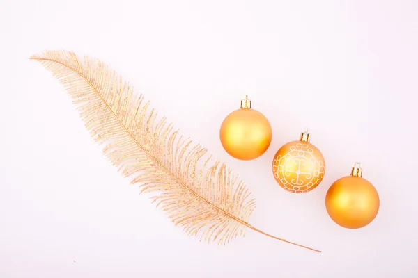 Three yellow shiny Christmas balls and yellow feather — Stock Photo, Image