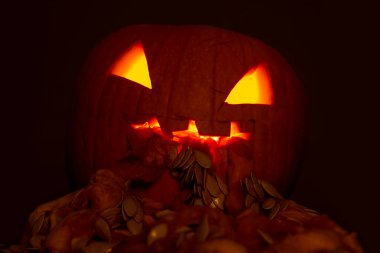 Cadılar Bayramı balkabağı feneri kusuyor, içinde de düşük açılı bir mum ışığı var.