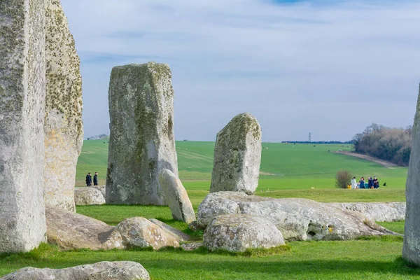 Arkasında yeşil çimenler ve bulutlu mavi gökyüzü olan Stonehenge