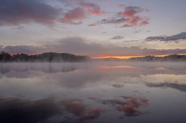 Whitford Gölü kıyılarının şafağında sisli sonbahar manzarası sakin sularda yansıyan yansımalarla, Fort Custer State Park, Michigan, ABD