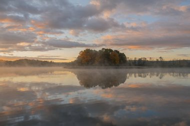 Whitford Gölü kıyılarının şafağında sisli sonbahar manzarası sakin sularda yansıyan yansımalarla, Fort Custer State Park, Michigan, ABD