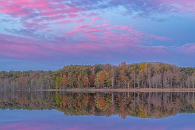 Derin Göl kıyılarının şafağında sonbahar manzarası sakin suda yansıyan yansımalarla, Yankee Springs State Park, Michigan, Usa