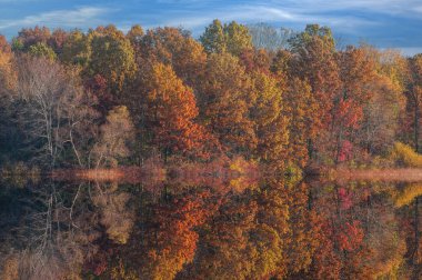Landscape of the autumn shoreline of Jackson Hole Lake with colorful reflections in calm water, Fort Custer State Park , Michigan, USA