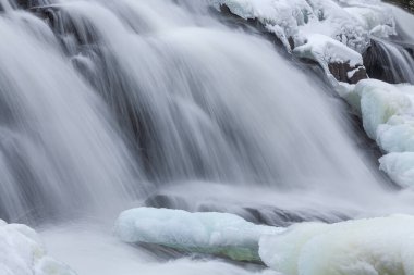 Winter landscape of Bond Falls framed by blue ice and snow and captured with motion blur, Ottawa National Forest, Michigan's Upper Peninsula, USA