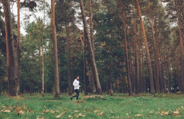 Sonbahar ormanında koşan bir kadın. Açık havada egzersiz yapmak.