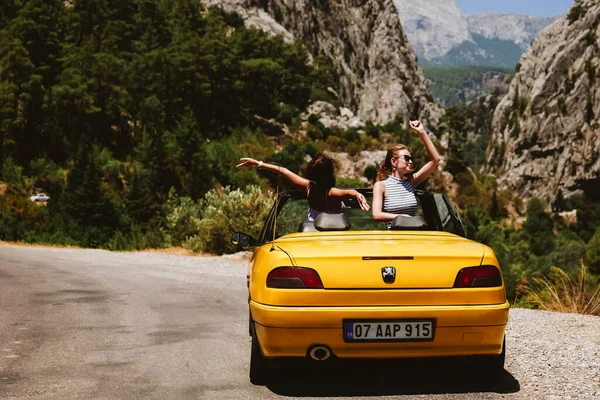 Deux jeunes femmes en voiture jaune profitant de vacances — Photo