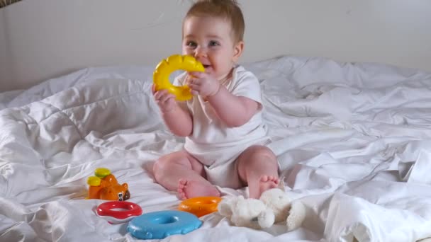 Förtjusande åtta månader gammal flicka leker med pyramidleksak sitter på sängen — Stockvideo