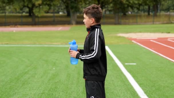 Adolescente Jogador Futebol Bebe Água Uma Garrafa Plástico Durante Treinamento — Vídeo de Stock