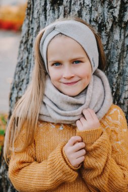 Sarı bluzlu, gri bantlı ve eşarplı sevimli kız. 