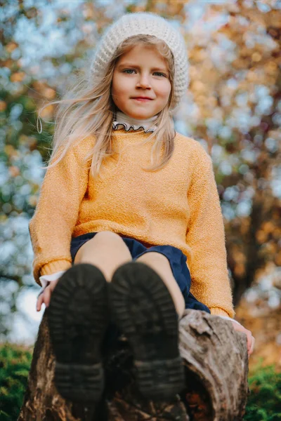 Schattig meisje in gele blouse en witte baret zittend op de boom — Stockfoto