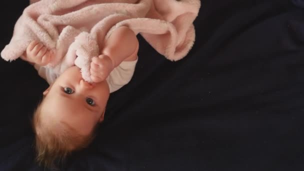 Schattig baby meisje liggend op donkere deken wakker — Stockvideo