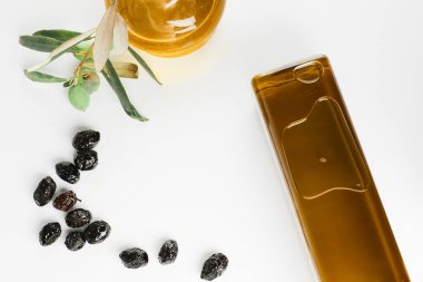 Cam şişelerde ekstra saf zeytinyağı ve beyaz arka planda tütsülenmiş zeytin..