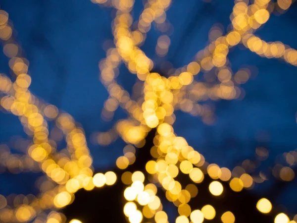 Рождественский фон с боке светящейся гирлянды на дереве — стоковое фото