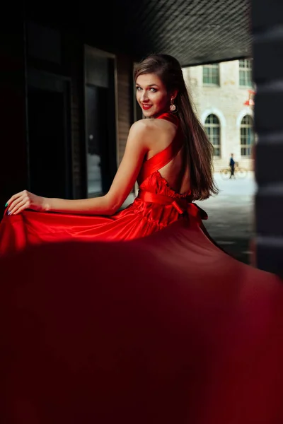 Jeune femme magnifique en robe rouge longue dans la ville moderne — Photo