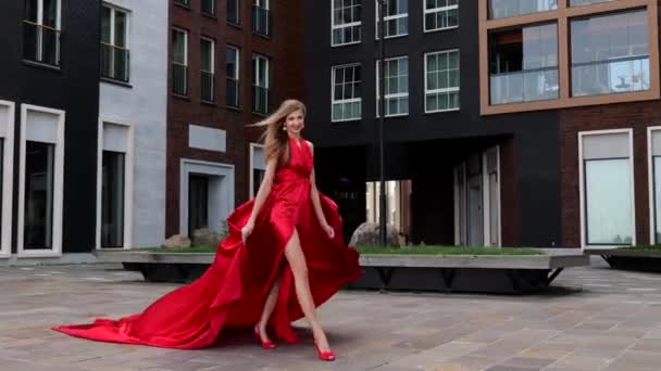 길고 빨간 드레스를 입은 젊고 아름다운 여자 가 도시를 걷고 있다 — 비디오