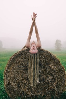 Alacakaranlık vakti samanlıkta uzanan bej elbiseli genç kadın.